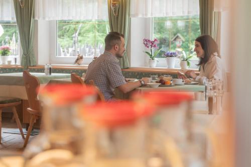 a man and woman sitting at a table in a restaurant at Hotel Lago della Creta in San Vigilio Di Marebbe