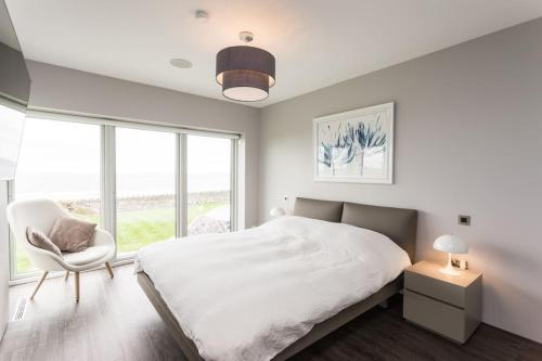 a white bedroom with a bed and a chair at Slate House in Ballybunion