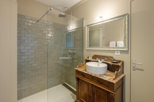 ein Bad mit einem Waschbecken und einer Glasdusche in der Unterkunft Le Domaine de Ravenoville - Pierres d'Histoire in Ravenoville