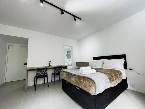 a bedroom with a large bed and a desk with chairs at Studio Duque Master in Porto Alegre
