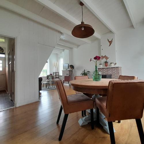 a dining room with a wooden table and chairs at Vakantiehuisje Mies Rust en stilte aan het strand in Hoofdplaat