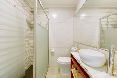 a white bathroom with a sink and a toilet at Above the Trees Close to the Sea in Estoril