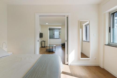 a white bedroom with a bed and a mirror at Above the Trees Close to the Sea in Estoril