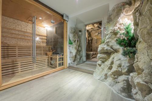 a bathroom with a stone wall and a shower in a room at Hotel Lago della Creta in San Vigilio Di Marebbe
