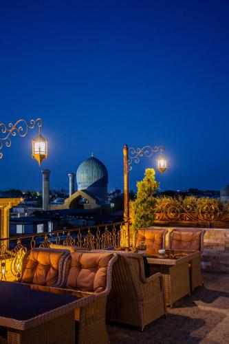 a couple of couches sitting on a balcony at night at Gur Emir Palace boutique hotel in Samarkand