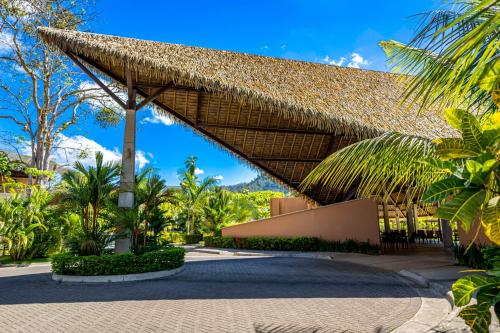 a resort with a thatched roof and palm trees at Casa Tranquila - Ciudad del Mar 90 in Jacó