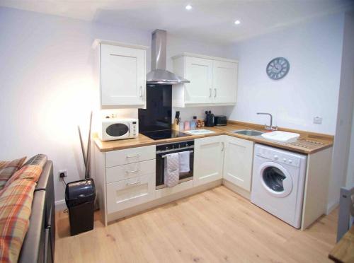 a kitchen with a washing machine and a microwave at Newly refurbished flat, 1 min from Galgorm resort in Cullybackey