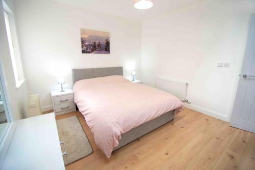 a bedroom with a bed with a pink bedspread at Newly refurbished flat, 1 min from Galgorm resort in Cullybackey