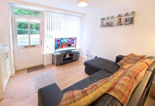 a living room with a couch and a tv at Newly refurbished flat, 1 min from Galgorm resort in Cullybackey
