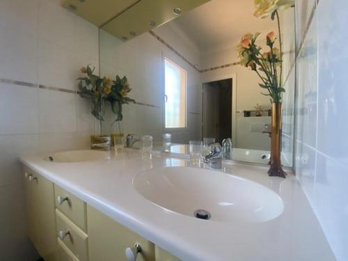 een badkamer met een witte wastafel en een spiegel bij Le Mas des Catalanes in Perpignan
