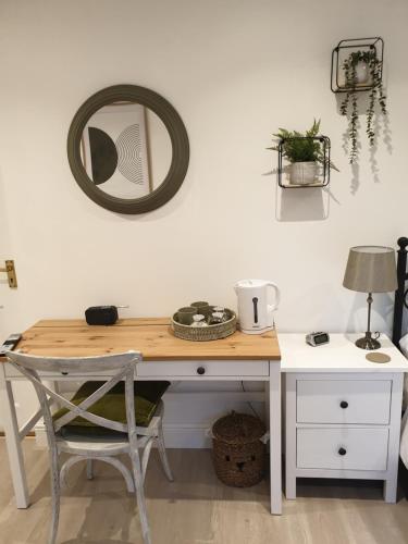 a desk with a chair and a mirror on the wall at Fly By in Duxford
