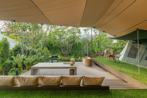 a wooden deck with a couch and an umbrella at CAMP CAYLA - EDEN in Chiang Mai