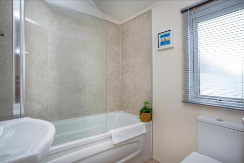 a bathroom with a tub and a sink and a toilet at Sunrise in Brixham
