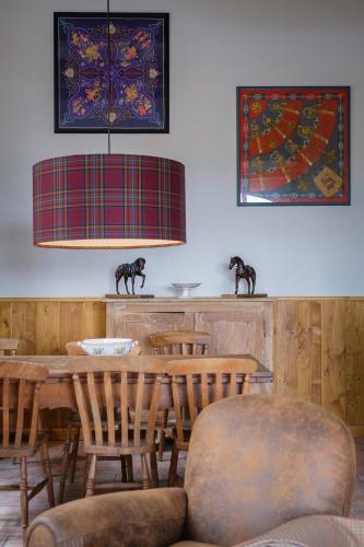 a dining room with a table and chairs and a lamp at Le Domaine de Ravenoville - Pierres d'Histoire in Ravenoville