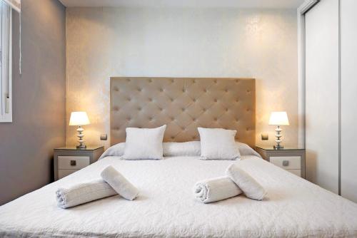 a bedroom with a large white bed with two lamps at La Perla in Chiclana de la Frontera