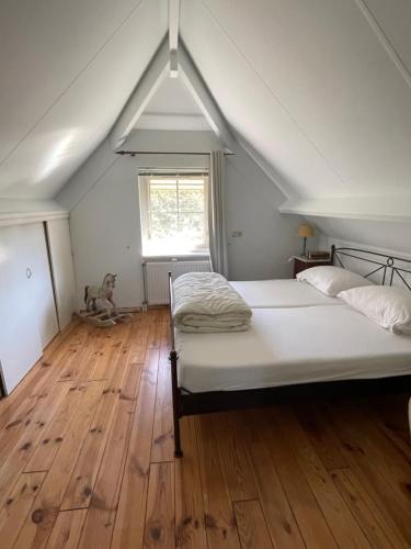 a bedroom with a bed and a wooden floor at Luxe vakantiewoning op de Goudsberg in Lunteren