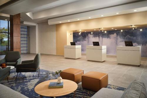 a lobby with a waiting area with chairs and tables at Sheraton Grand Rapids Airport Hotel in Grand Rapids