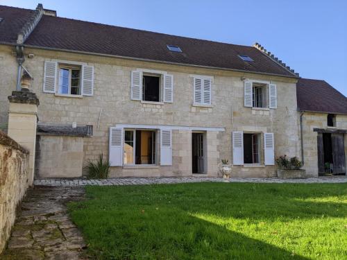 a large stone house with white windows and a yard at Maison de campagne in Ambleny