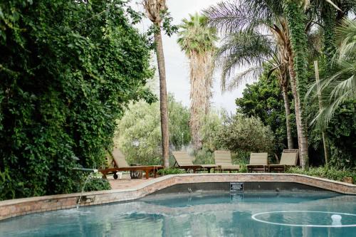 a swimming pool in a yard with chairs and trees at Upington African Vineyard Boutique Hotel & SPA in Kanoneiland