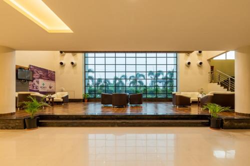 a lobby with couches and chairs and a large window at Monk's Nirvanaa Hotel & Resort in Indore
