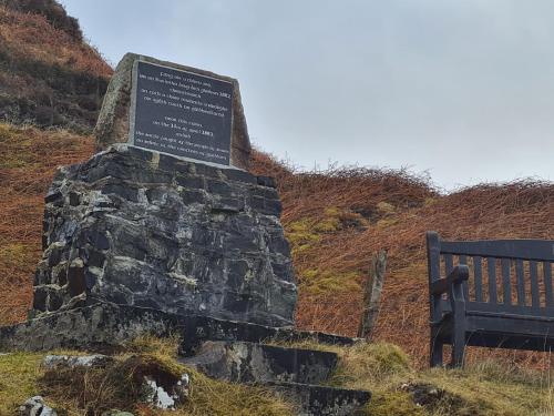 a bench sitting next to a sign on a hill at Hillend Self-Catering in Portree