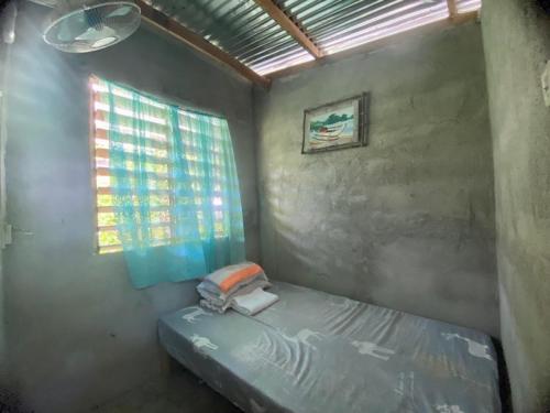 Habitación pequeña con cama y ventana en Punta Landing Travellers Inn, en Surallah