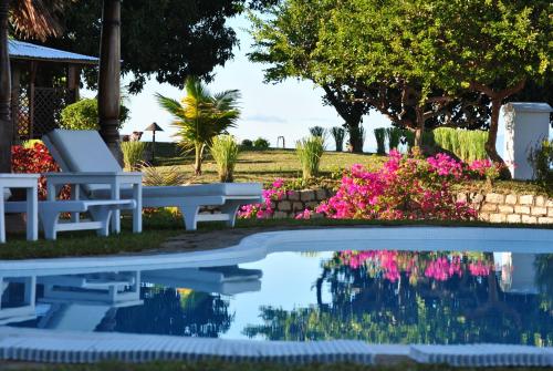 a swimming pool with a bench and flowers at Villa Palissandre in Nosy Be