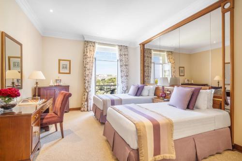 a hotel room with two beds and a desk at Palácio Estoril Hotel, Golf & Wellness in Cascais