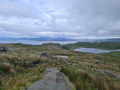 a dirt road through a grassy hill with a lake at Hillend Self-Catering in Portree