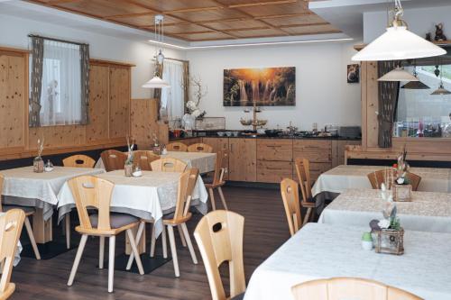 a restaurant with tables and chairs and a kitchen at Apparthotel Sonnwies in Selva dei Molini