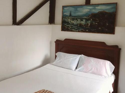 a bedroom with a white bed with a painting on the wall at Sapiens house "cabaña del Río" in Cali