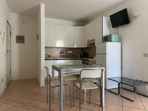 Una cocina con mesa y sillas y un refrigerador. en Residenza Verdi Milano Marittima, en Milano Marittima