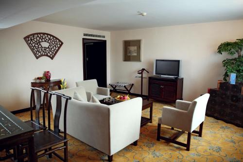 a living room with a couch and chairs and a tv at Garden Hotel Suzhou in Suzhou