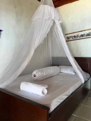 uma cama com uma rede mosquiteira e 2 toalhas em Mangkombong Homestay em Tapokreng