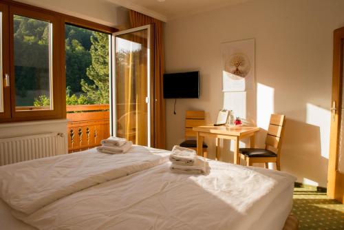 a bedroom with a bed and a desk and a window at Dorfpension Mariahilfberg in Gutenstein