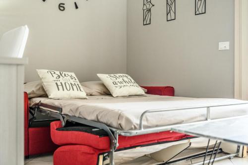 uma cama num quarto com um sofá vermelho e almofadas em Moderna Suite con ampio terrazzo - Free WiFi & Parking em SantʼAgata sul Santerno