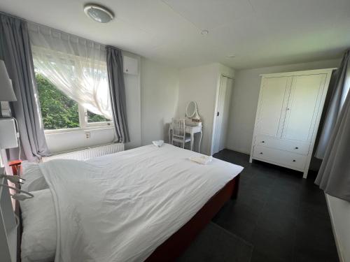 um quarto com uma grande cama branca e uma janela em Ruime chalet midden in de natuur in Lith em Lith