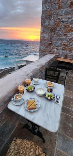 a table with plates of food on it with the ocean at Arapis Rooms & Suites in Áyios Kiprianós