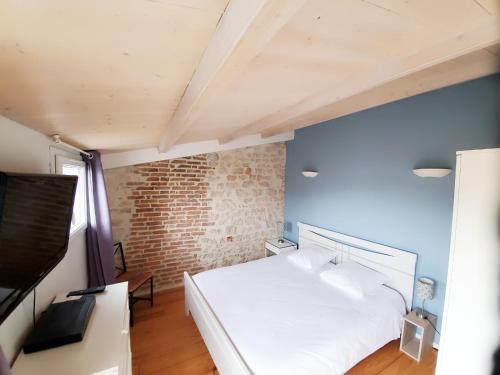 une chambre avec un lit blanc et un mur de briques dans l'établissement Les Marionnettes, Maison de ville 80m2 avec terrasse, à La Rochelle