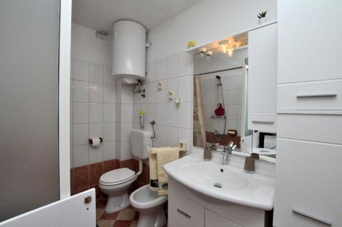 bagno bianco con servizi igienici e lavandino di Apartments Lory a Rabac