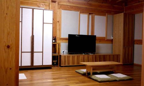 a living room with a flat screen tv and a table at Hwangnamguan Hanok Village in Gyeongju