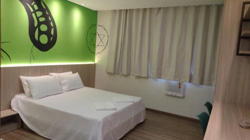 a bedroom with a white bed and a green wall at Pousada Boutique Raio de Luz in Ouro Preto