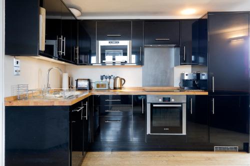 a kitchen with black cabinets and a counter top at ALTIDO Charming flat overlooking River Thames in London