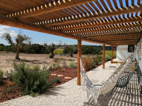 a hammock under a wooden pergola in a garden at Castelo de Arez in Alcácer do Sal