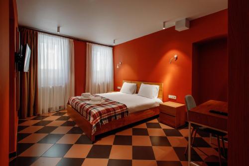 a bedroom with a bed with orange walls and a checkered floor at Urban Apartments 23 in Tbilisi City