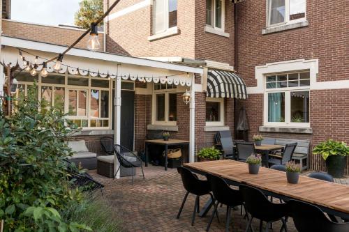 a patio with a table and chairs in front of a building at VillaEnzo - ELEGANT HERENHUIS - 14P - 6SLPK - SAUNA - INFRAR CABINE - OFYR BBQ - 15MIN Maastricht in Zussen