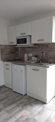 a white kitchen with white cabinets and a sink at Studio "l'aube du Perche" in La Mancelière
