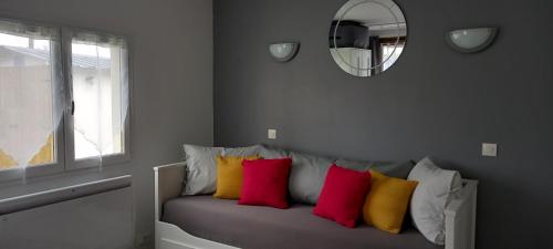 a bench with colorful pillows sitting under a mirror at Studio "l'aube du Perche" in La Mancelière