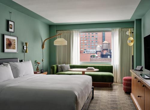 ニューヨークにあるRomer Hell's Kitchenのベッド、ソファ、窓が備わるホテルルームです。