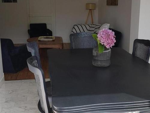 a black table with a vase of pink flowers on it at Maison rénovée avec jardin clos, proche du centre historique, idéale pour famille ou télétravail - FR-1-489-439 in Moulins
